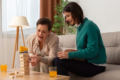 Two women playing Jenga in a cozy living room.