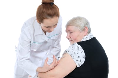 A healthcare professional administering a vaccine to an elderly woman.