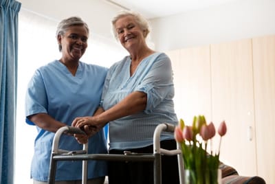 Nurse assisting senior resident with walker