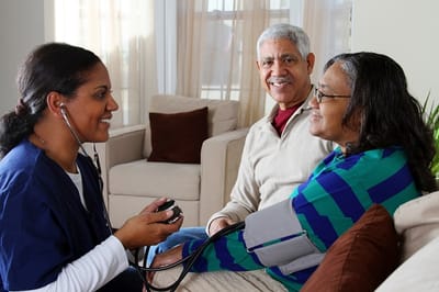 Nurse checking vital signs of seniors in a cozy setting.