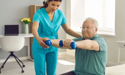 Caregiver assisting elderly man with weights