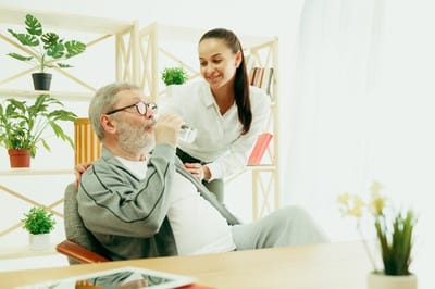 Staff assisting a senior resident in a bright room.