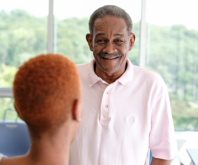 Older man smiling with another person in conversation