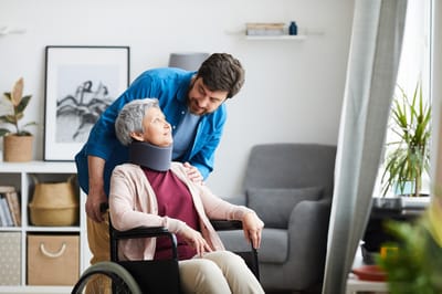 Caregiver assisting a senior woman in a wheelchair.