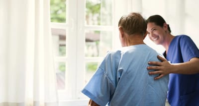 Caregiver smiling with a senior resident by the window