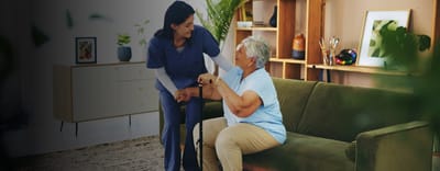 A caregiver helping a senior resident in a cozy living room.