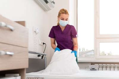 Staff member changing bedding in a resident's room.