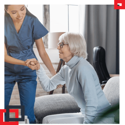 Staff assisting a senior resident in a cozy interior setting.
