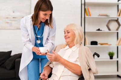 Nurse assisting senior woman in a care setting.