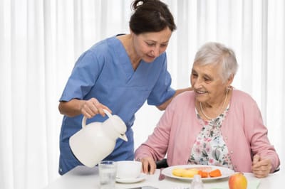 Caregiver serving food to an elderly resident