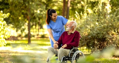 Caregiver assisting an elderly man in a garden