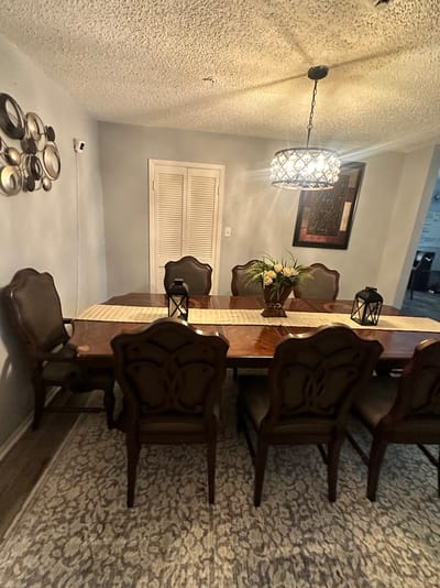 A dining room with a large wooden table and chairs.