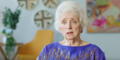 Senior woman in a vibrant purple outfit indoors.