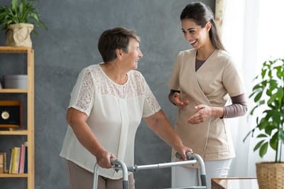 Staff assisting a resident indoors with a walker.