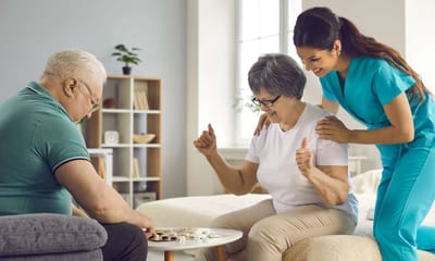 Care staff engaging residents in a board game activity.