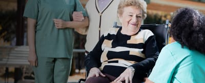 Happy elderly resident interacting with staff outdoors.