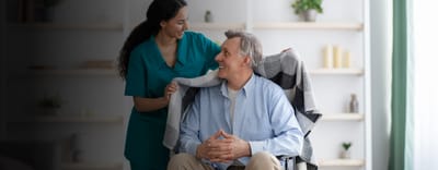 Nurse assisting a senior man in a common area.