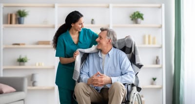 Caregiver assisting a senior man in a chair.