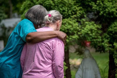 Caregiver hugging a resident in a garden