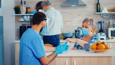 Healthcare worker assisting senior in kitchen.