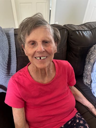 Smiling elderly woman sitting on a couch.