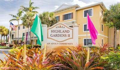 Exterior view of Highland Gardens II Apartments with flags and landscaping