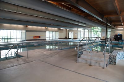 Indoor pool area with accessible stairs and windows