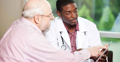 A doctor assisting a senior resident with a tablet