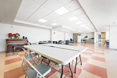 Bright interior view of a common area with tables and piano