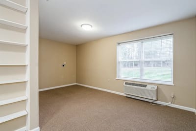 Interior view of a resident room with carpet and window