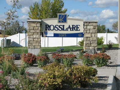 Outdoor sign for Rosslare Senior Apartments with landscaping