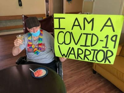 Resident holding a sign celebrating resilience during COVID-19