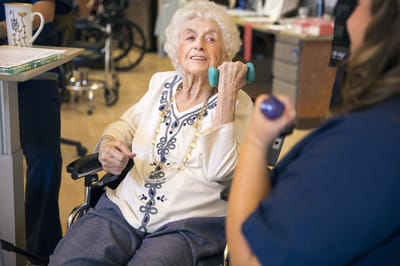 Elderly resident engaging in exercise with a staff member