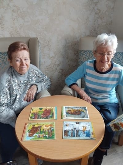 Two residents engaging with puzzles in a common area