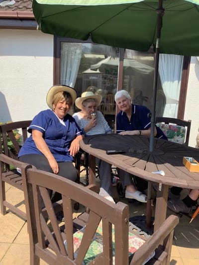 Staff and residents enjoying time outdoors at a table
