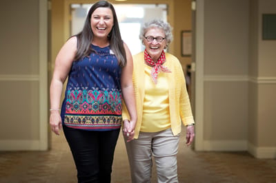 Two women walking and laughing in a hallway