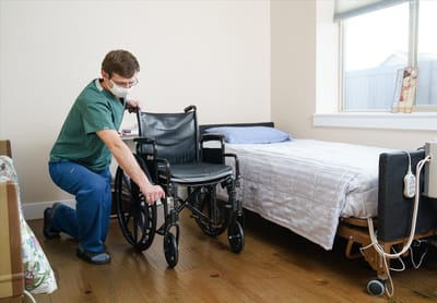 Staff member adjusting a wheelchair in a resident room