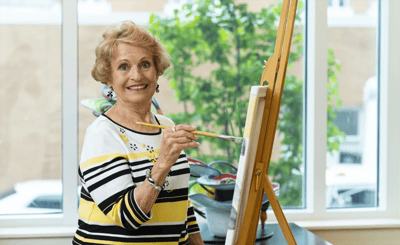 Resident painting at an easel in a bright room