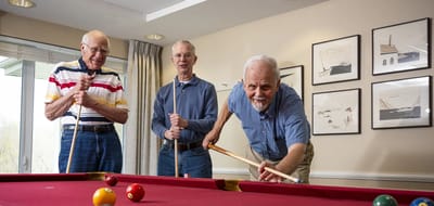 Residents playing billiards in a common room