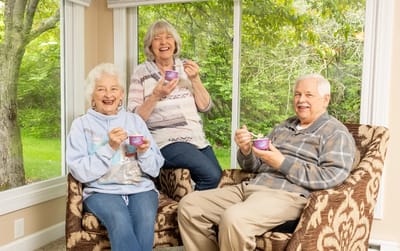 Three residents enjoying ice cream in a sunny lounge