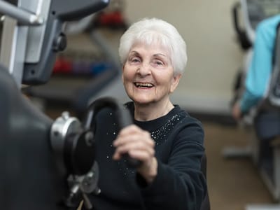 Elderly woman exercising on fitness equipment
