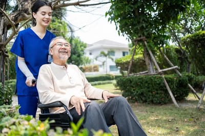 A caregiver assisting a smiling resident in a garden