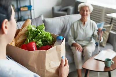 A caregiver delivering groceries to a senior resident