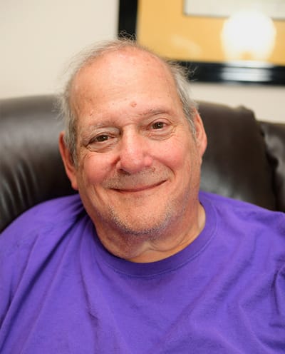 A smiling resident in a purple shirt