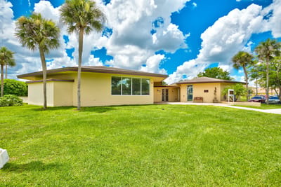 Exterior view of the facility surrounded by grass and palm trees
