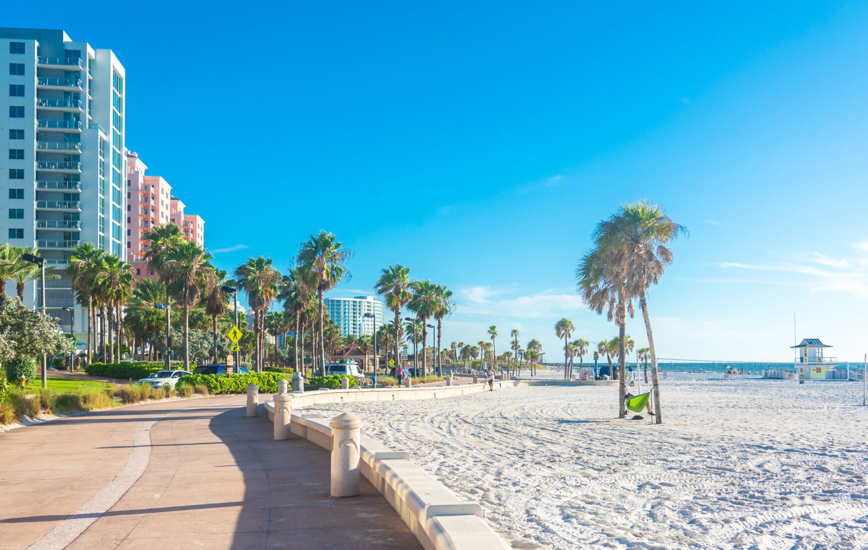 Scenic beach walkway with palm trees and buildings