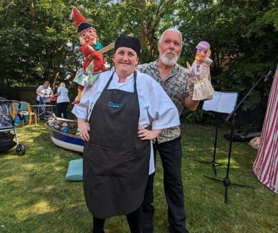 Staff member and performer with puppets in a garden