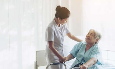 Nurse assisting an elderly woman in a care setting.