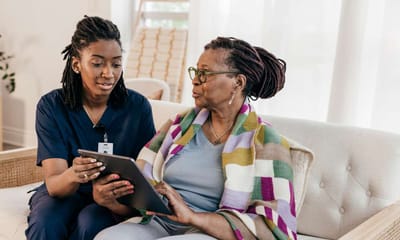 Caregiver assisting a senior with a tablet.