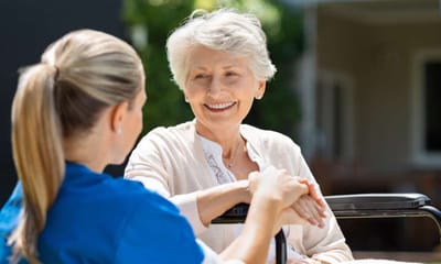 Caregiver interacting with a senior resident outdoors.